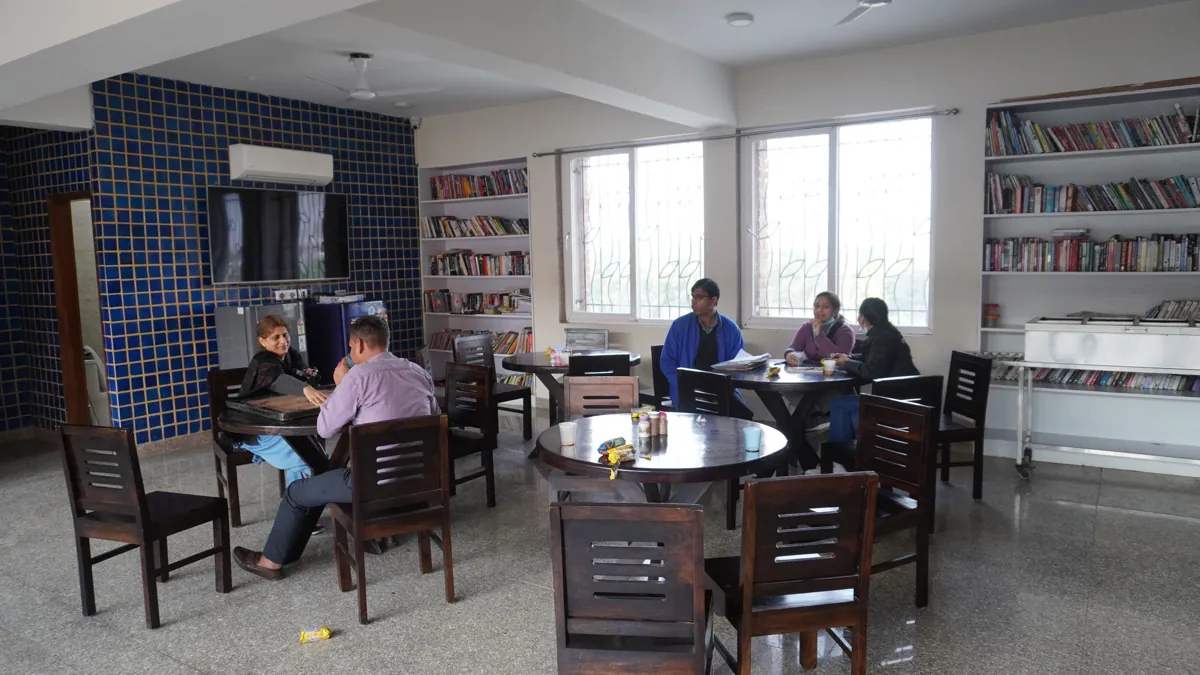 Residents reading and talking together in the library at the Gurugram centre