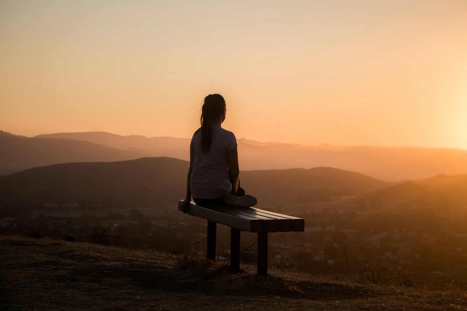Woman sitting on bench over viewing mountain